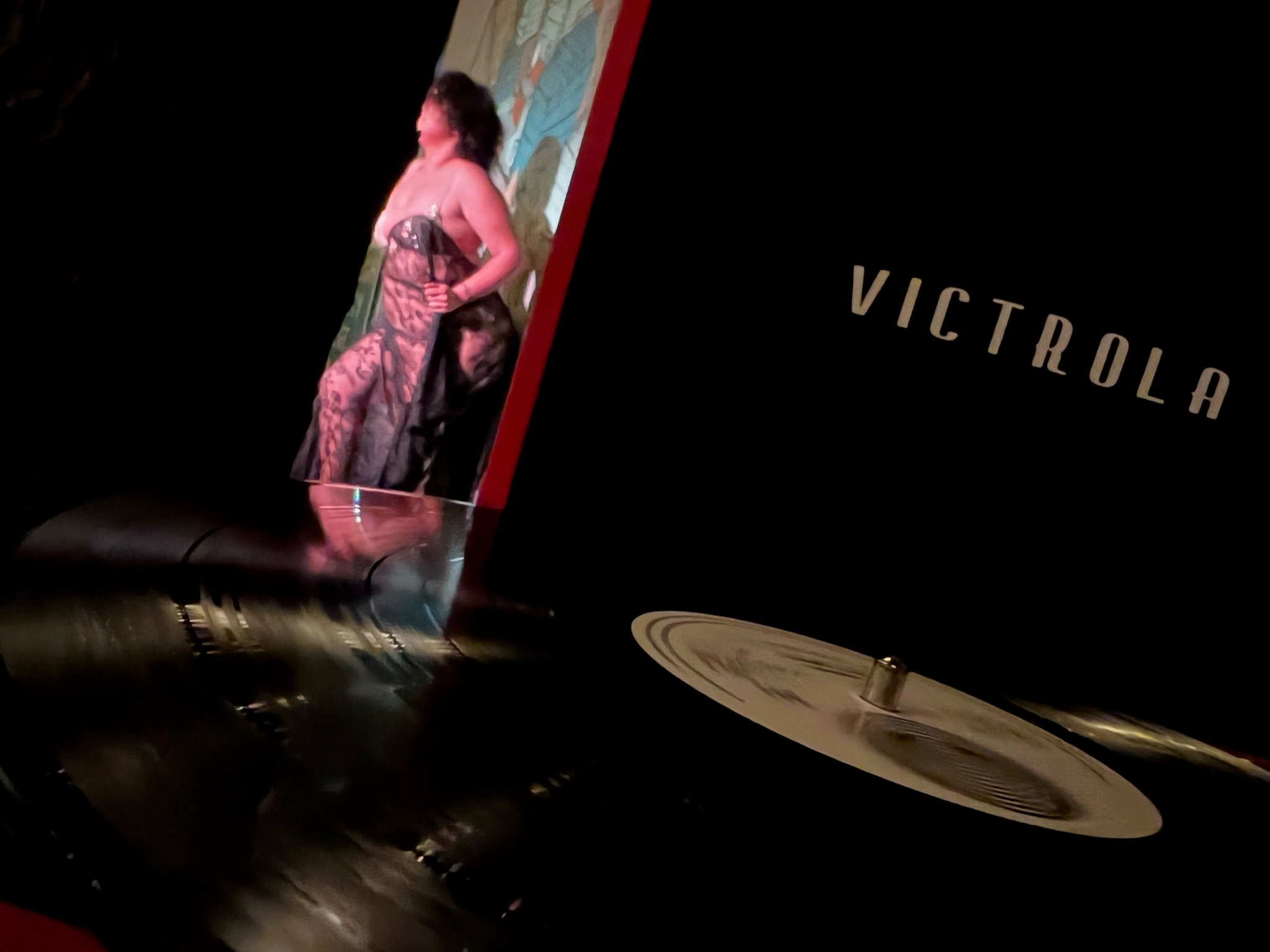 a burlesque dancer, blurred in the background, is refracted in the grooves of a vinyl