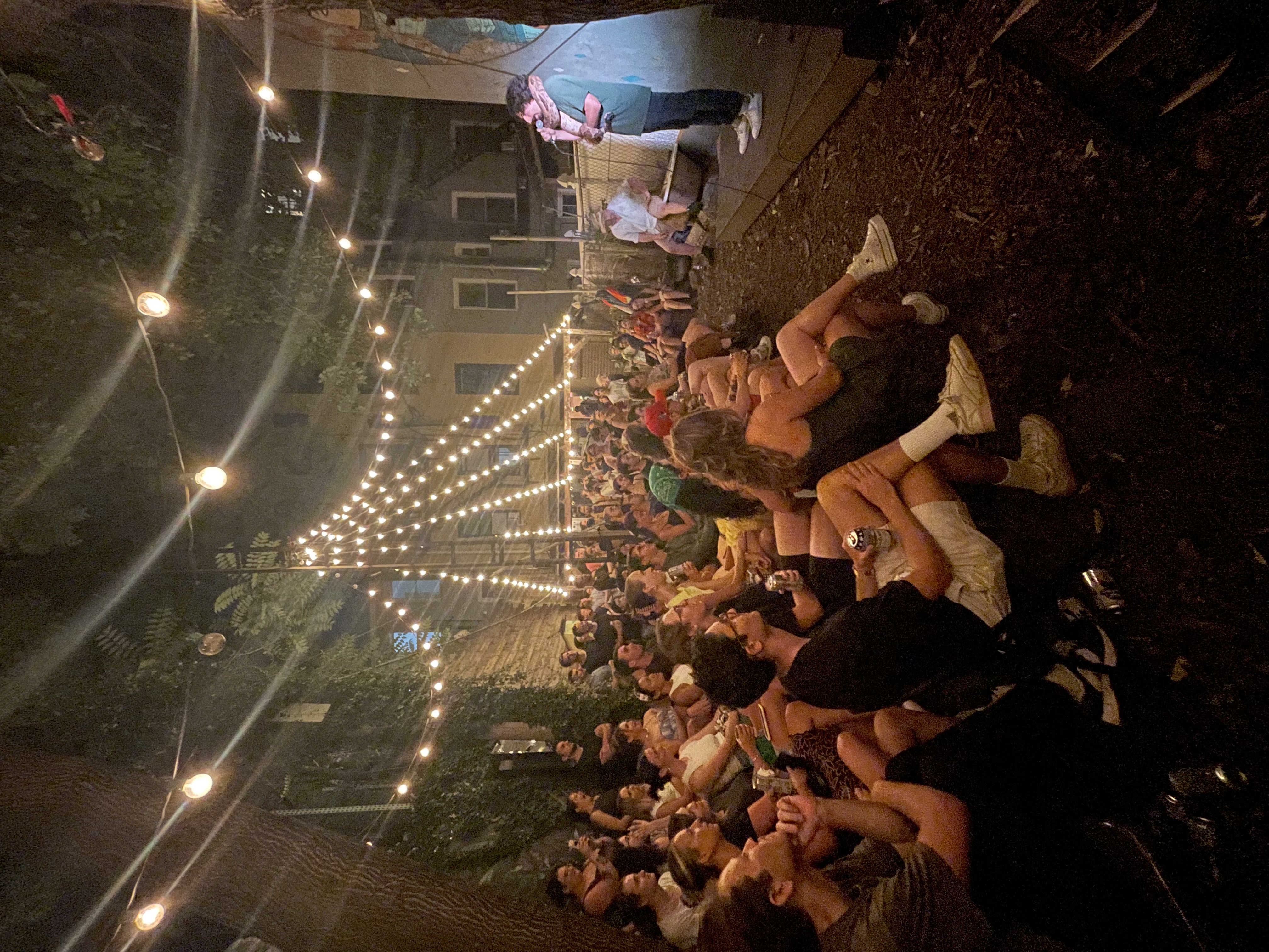 Mike of Petting Zoo stands in front of a crowd of over a hundred, holding a microphone and a boa constrictor