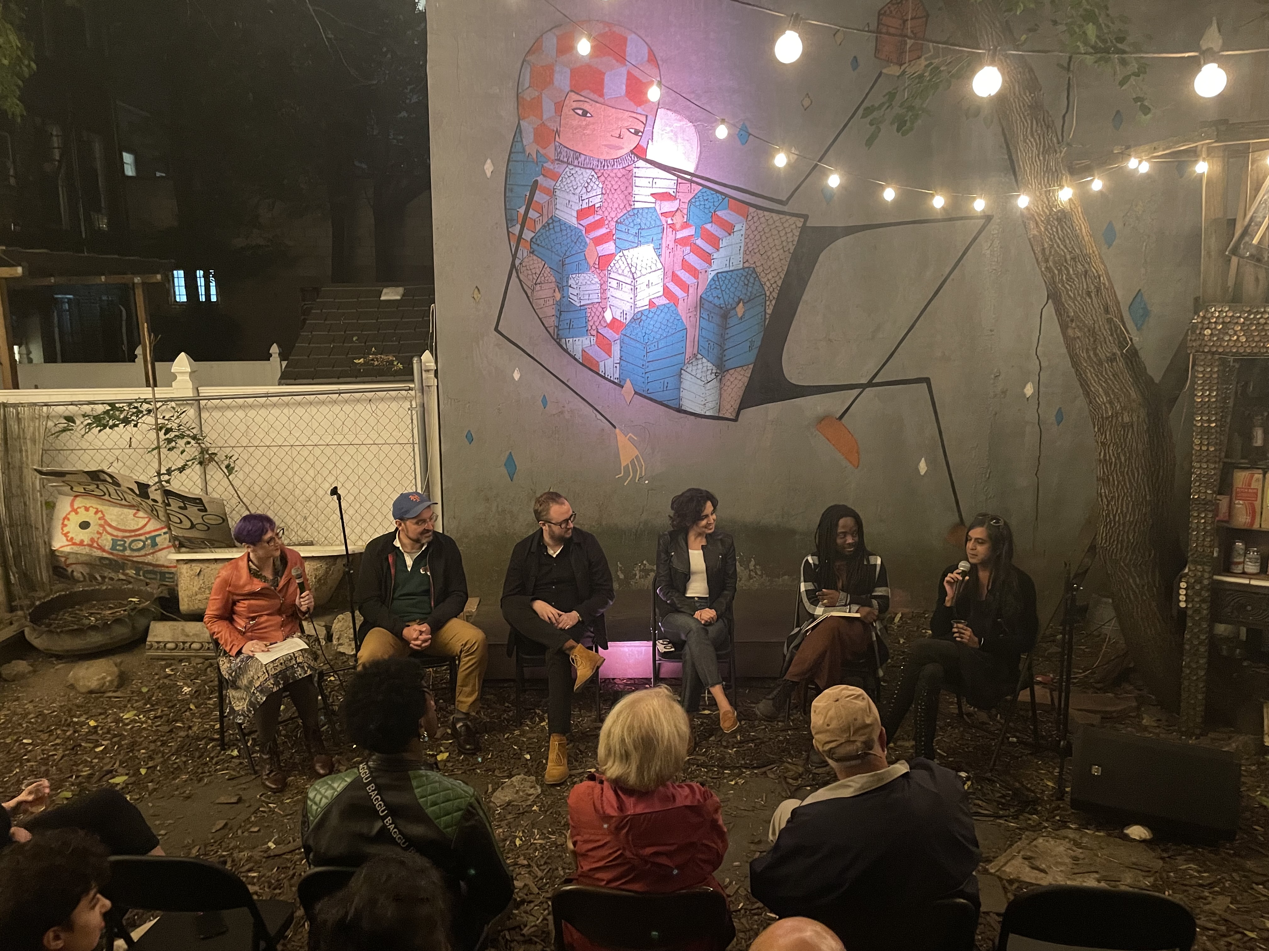 a panel of five face a listening crowd